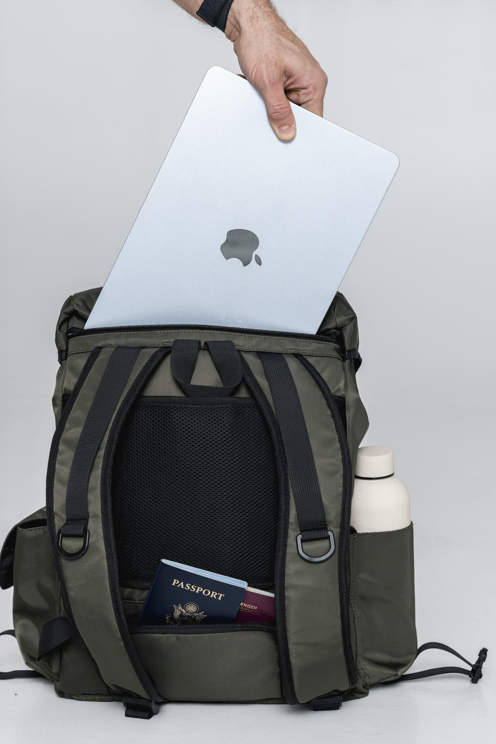 Laptop being placed into the Olive Cruiser's rear compartment, with a passport in its back pocket